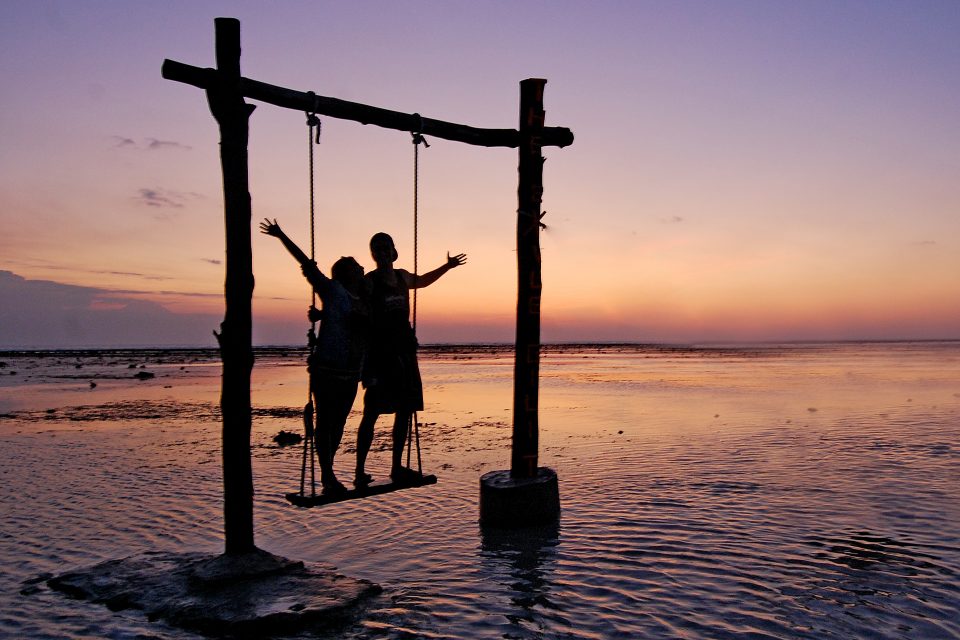 A couple's silhouette on a swing at sunset