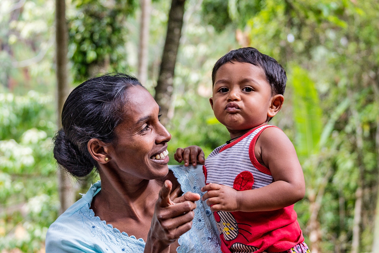 Portrait of young adult woman embracing little baby and pointing finger to the camera in Ella Sri Lanka