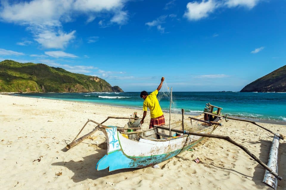 Fisherman in old boat at beach on Lombok, Indonesia