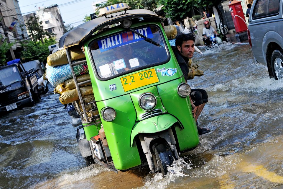 An auto rickshaw drives through rain