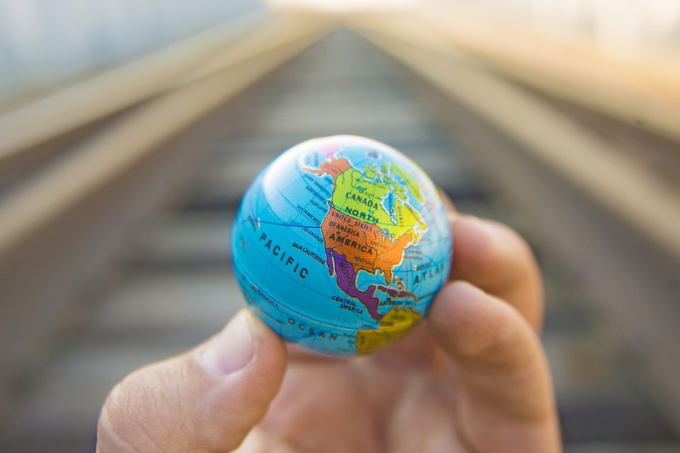 A hand holding a small globe