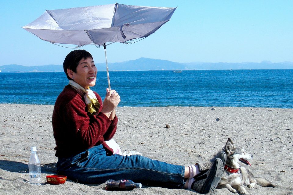 A woman sitting on the beach with an umbrella