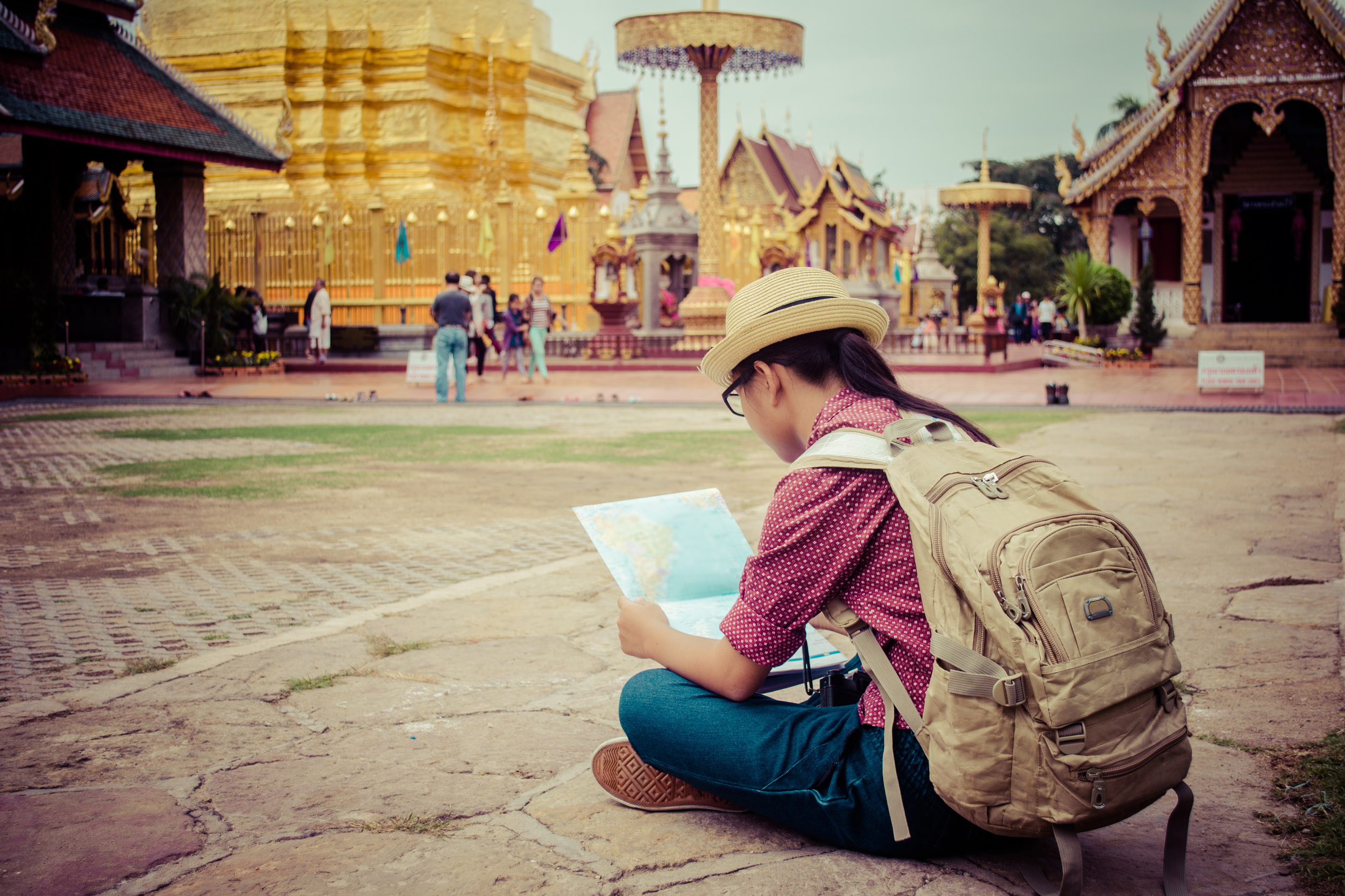 A woman sitting in front of a temple looking at a map