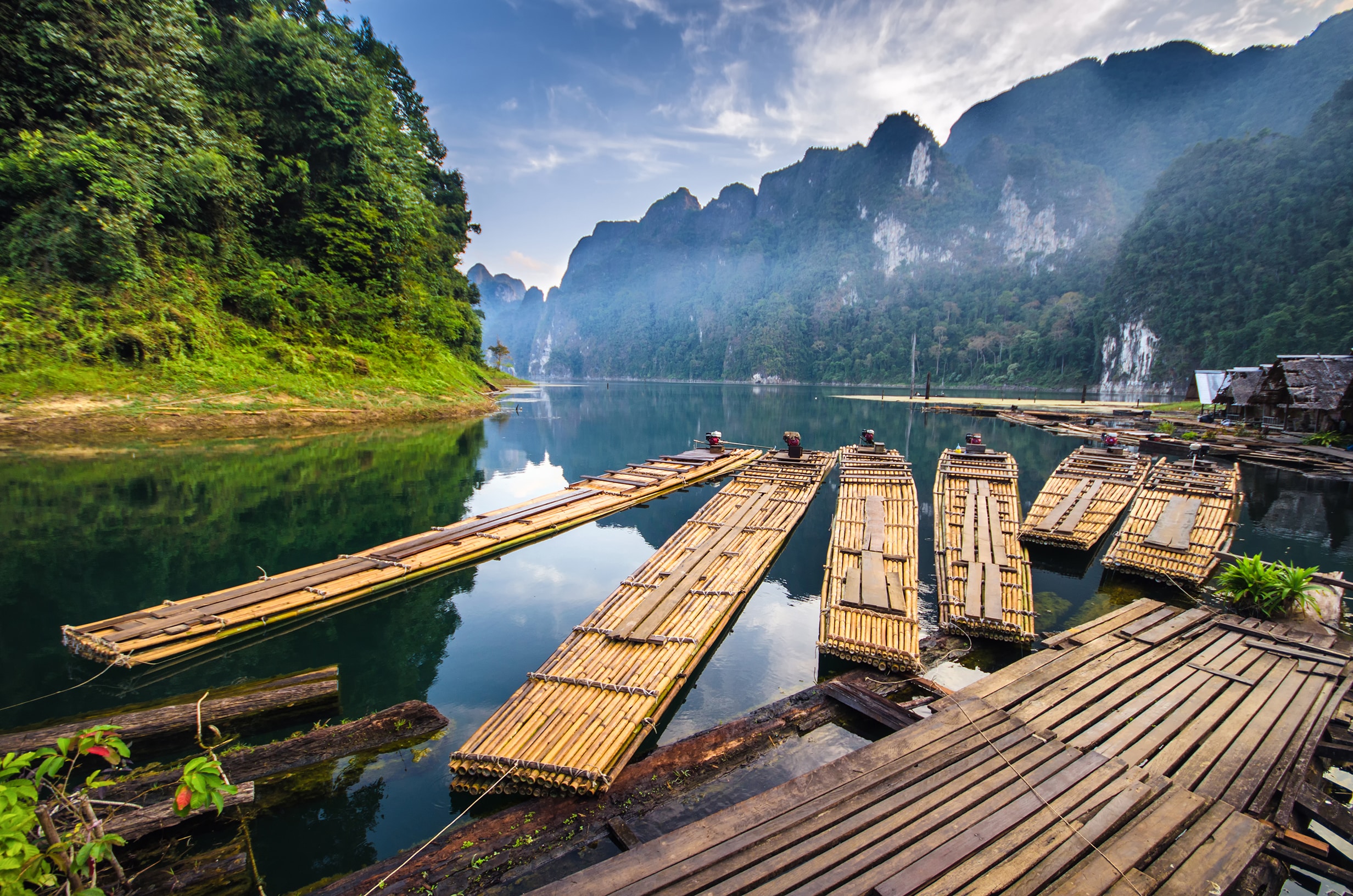 Bamboo rafts moored to a deck with mountains behind