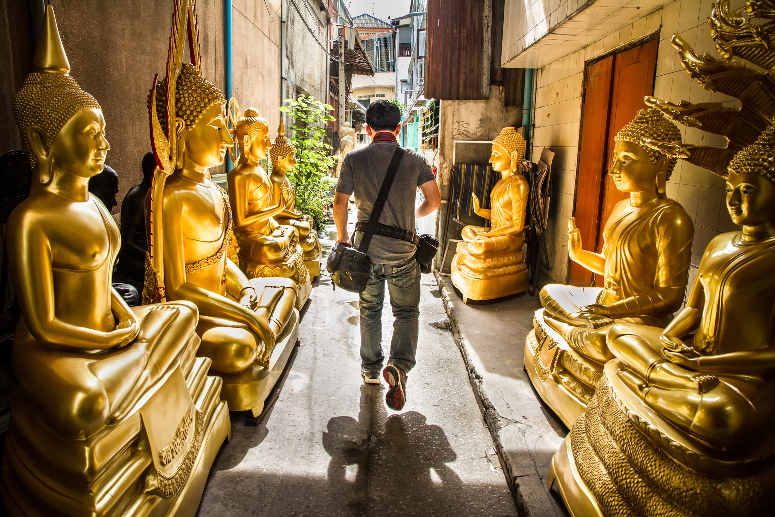 A man walking through the street lined with buddhas