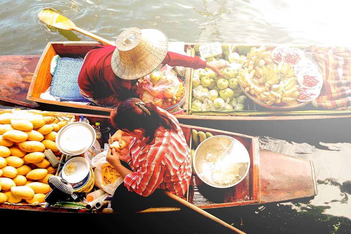 Two women selling fruit from canoes