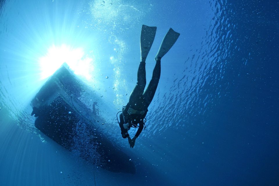 Upwards view of a diver surfacing at a boat