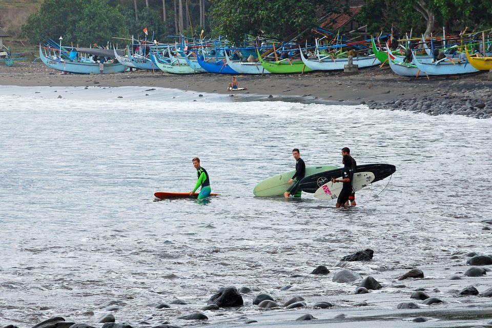 A group of people carrying surf boards into the sea