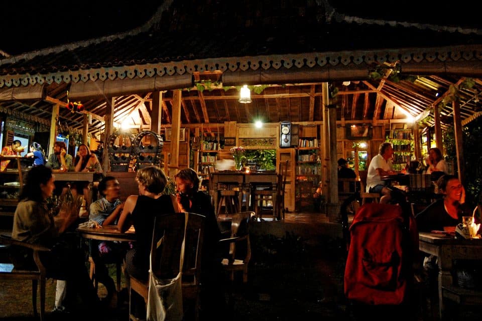 People sitting outside a wooden hut restaurant
