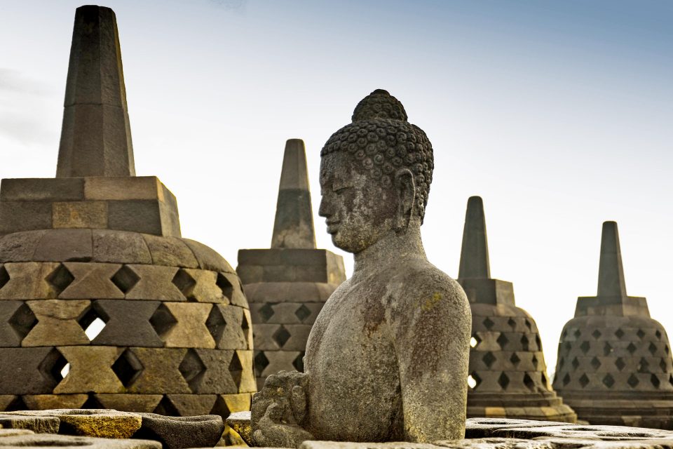 A stone buddha in front of temples
