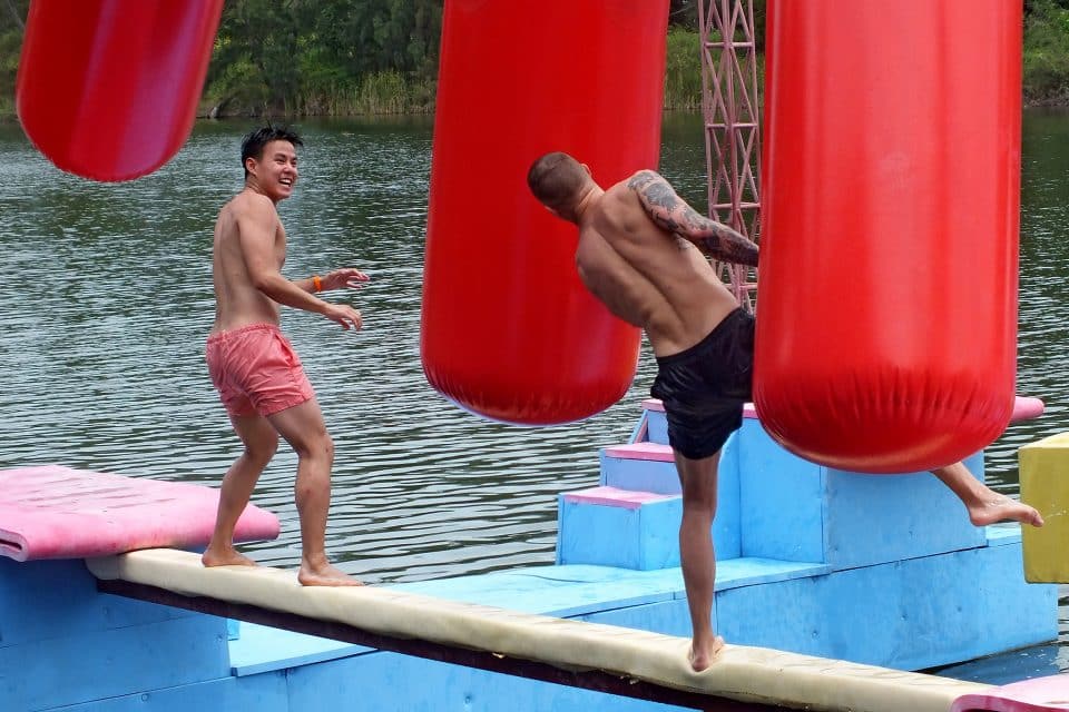 Two men on a balance beam over water