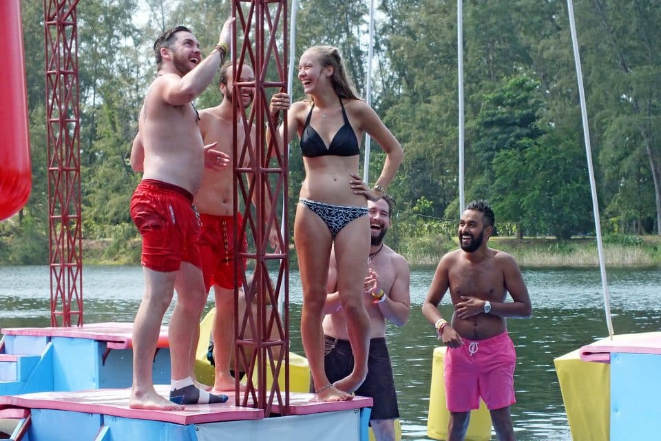 A group of people standing on a floating assault course laughing