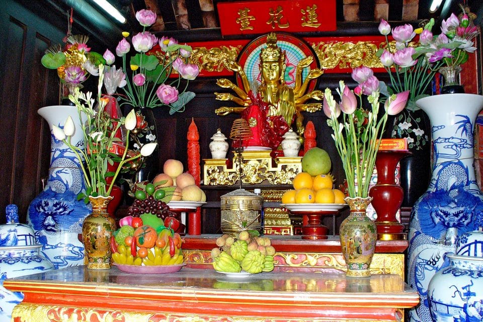 A golden buddha with bowls of fruit as offerings