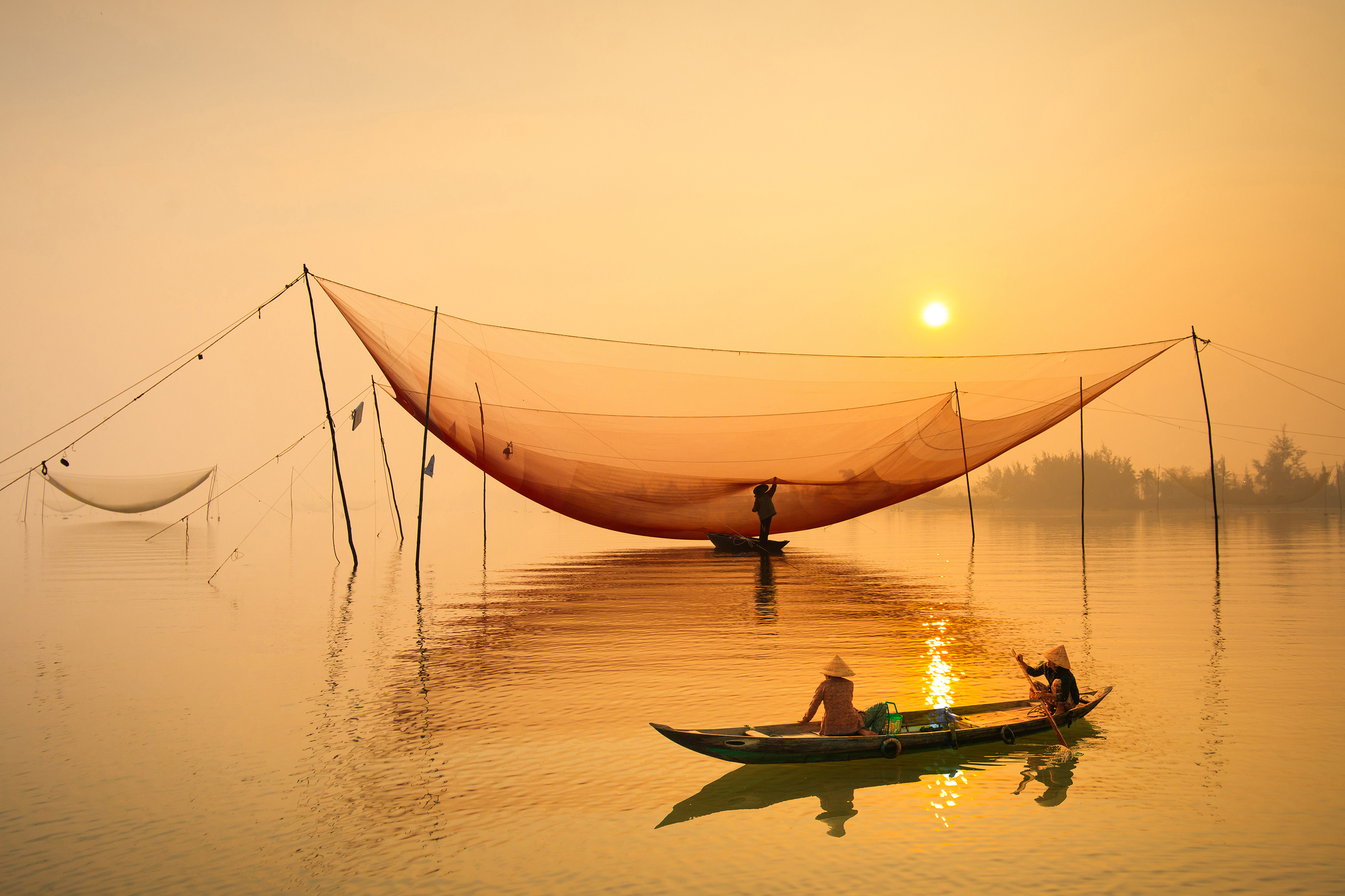 Two local people fishing from a canoe at sunset