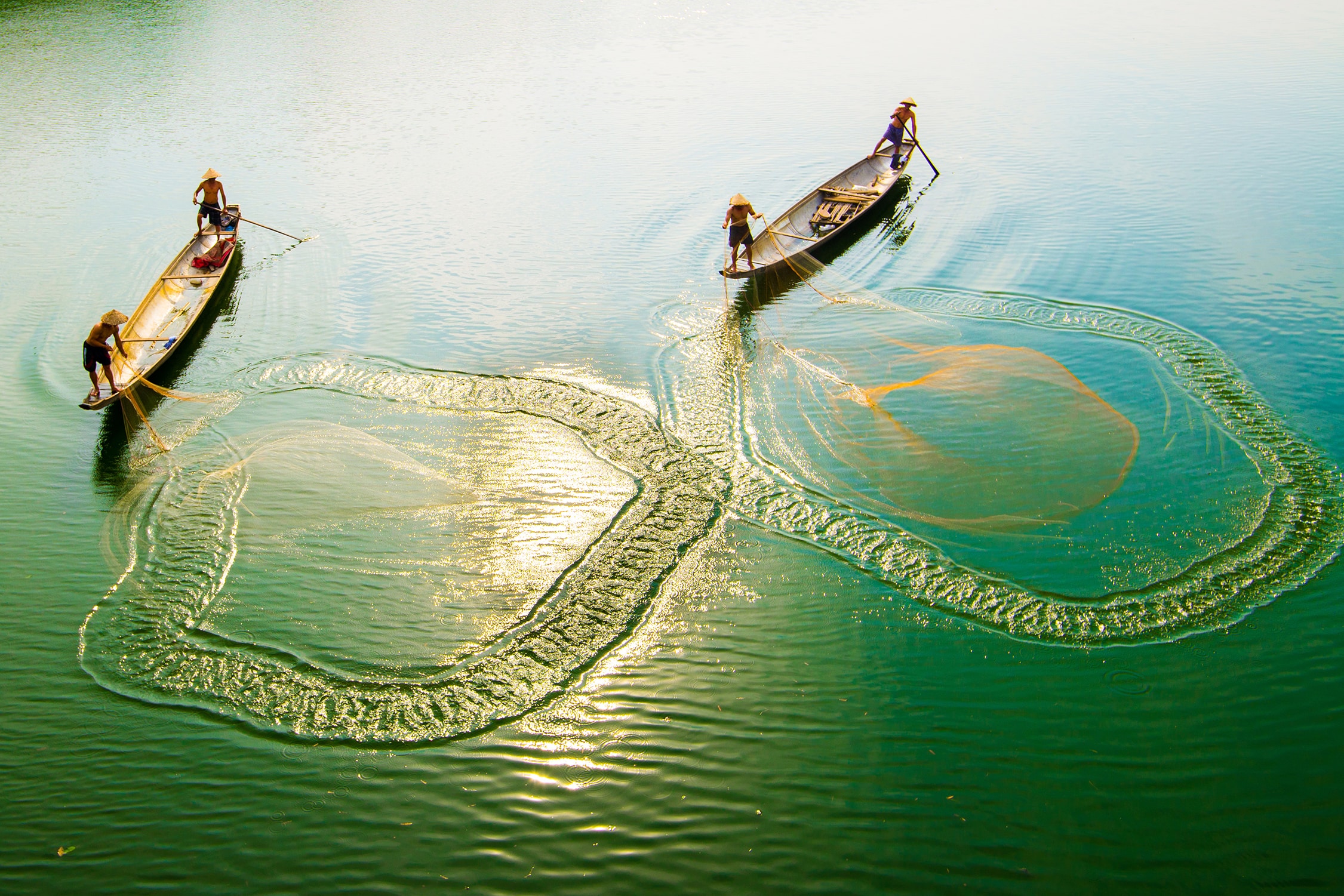 Local people casting fishing nets from their canoes