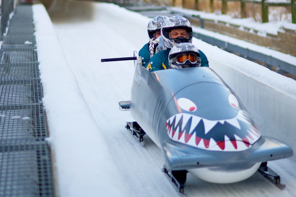 Three men in a bobsleigh on a course