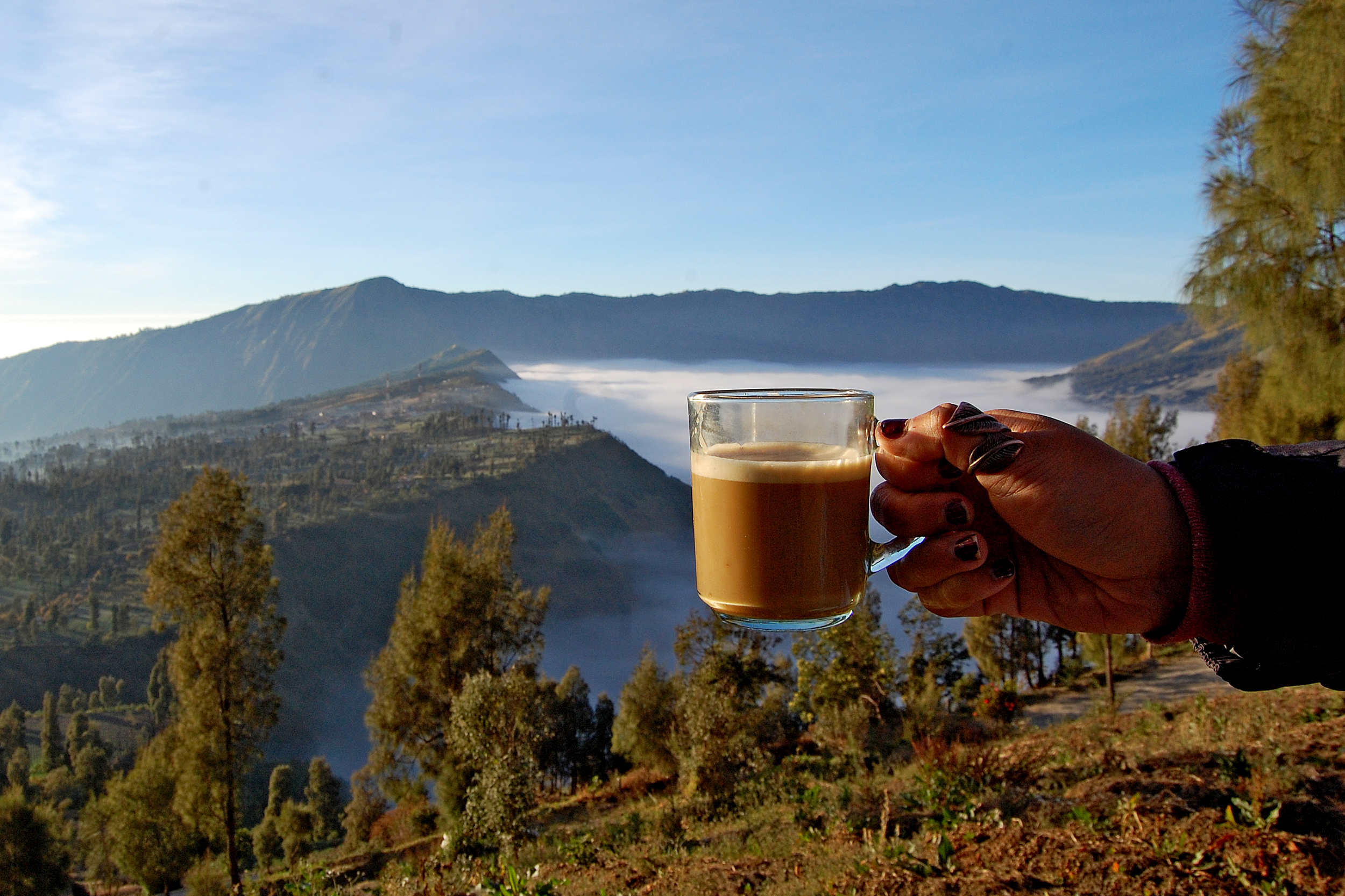 A cup of coffee in front of mountain views through the clouds