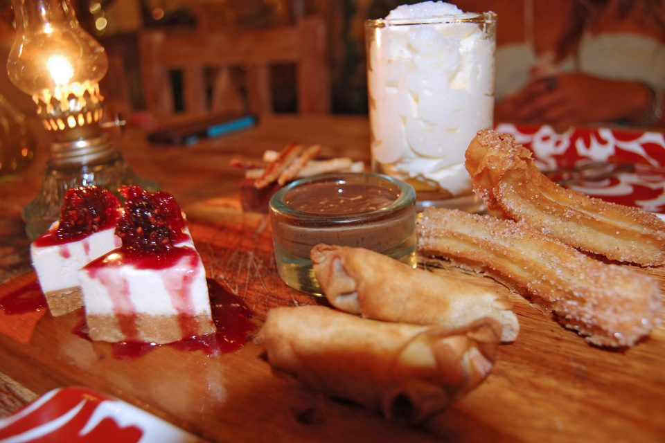 Close up of a desert platter with churros and cheesecake