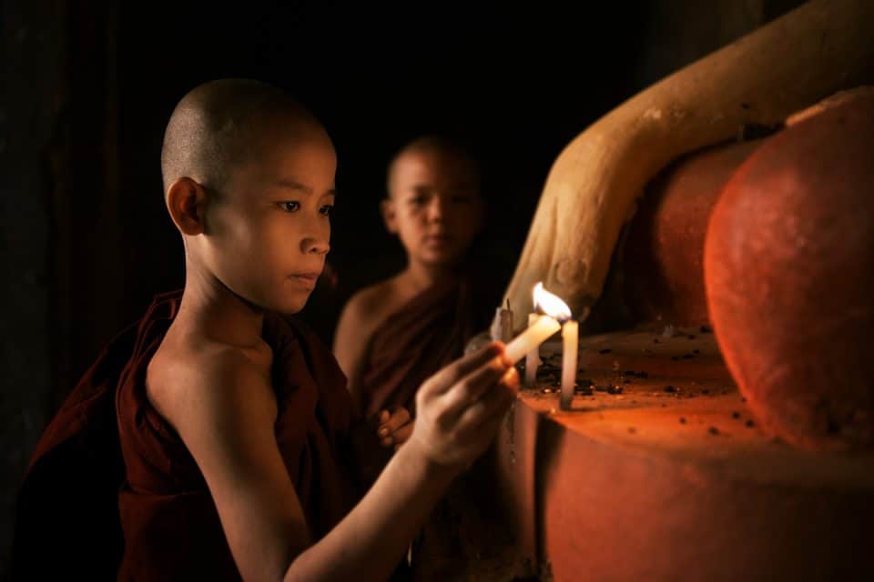 Small child lights a candle in Myanmar