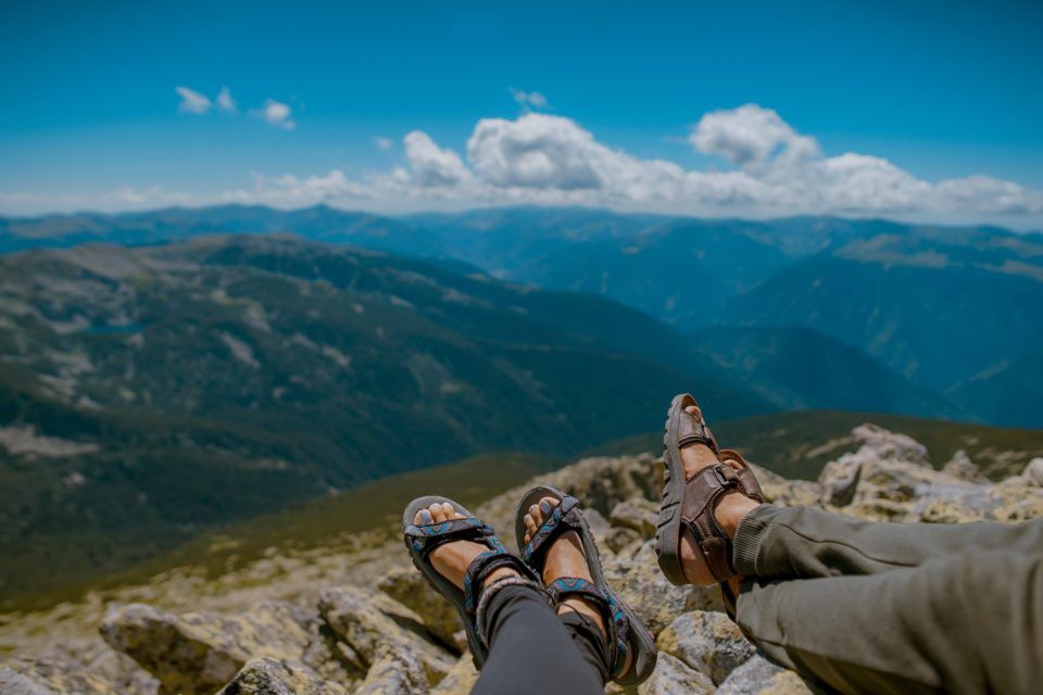 Two people sitting on top of a mountain in sandals