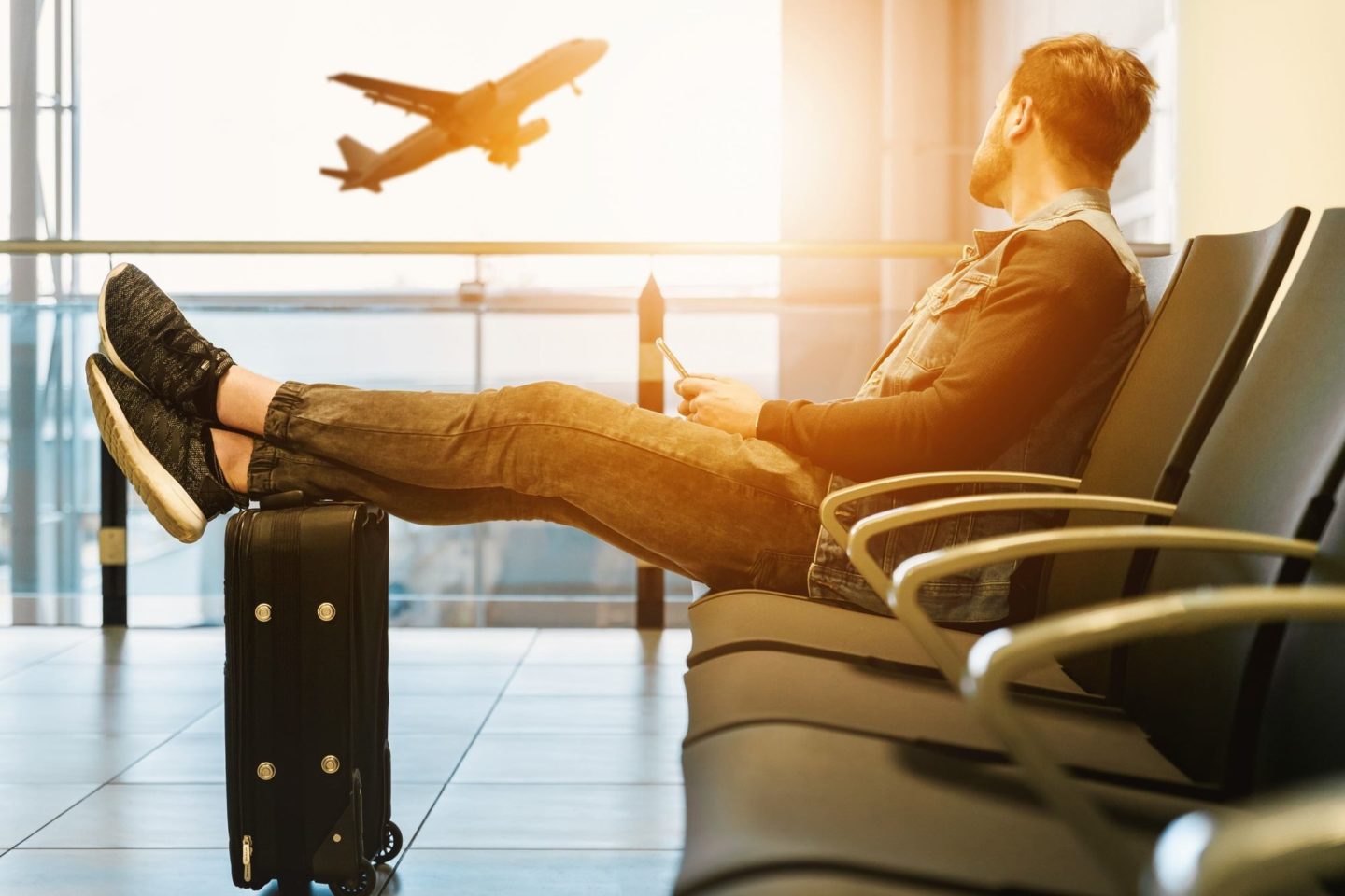 Man watching airplane with feet on luggage