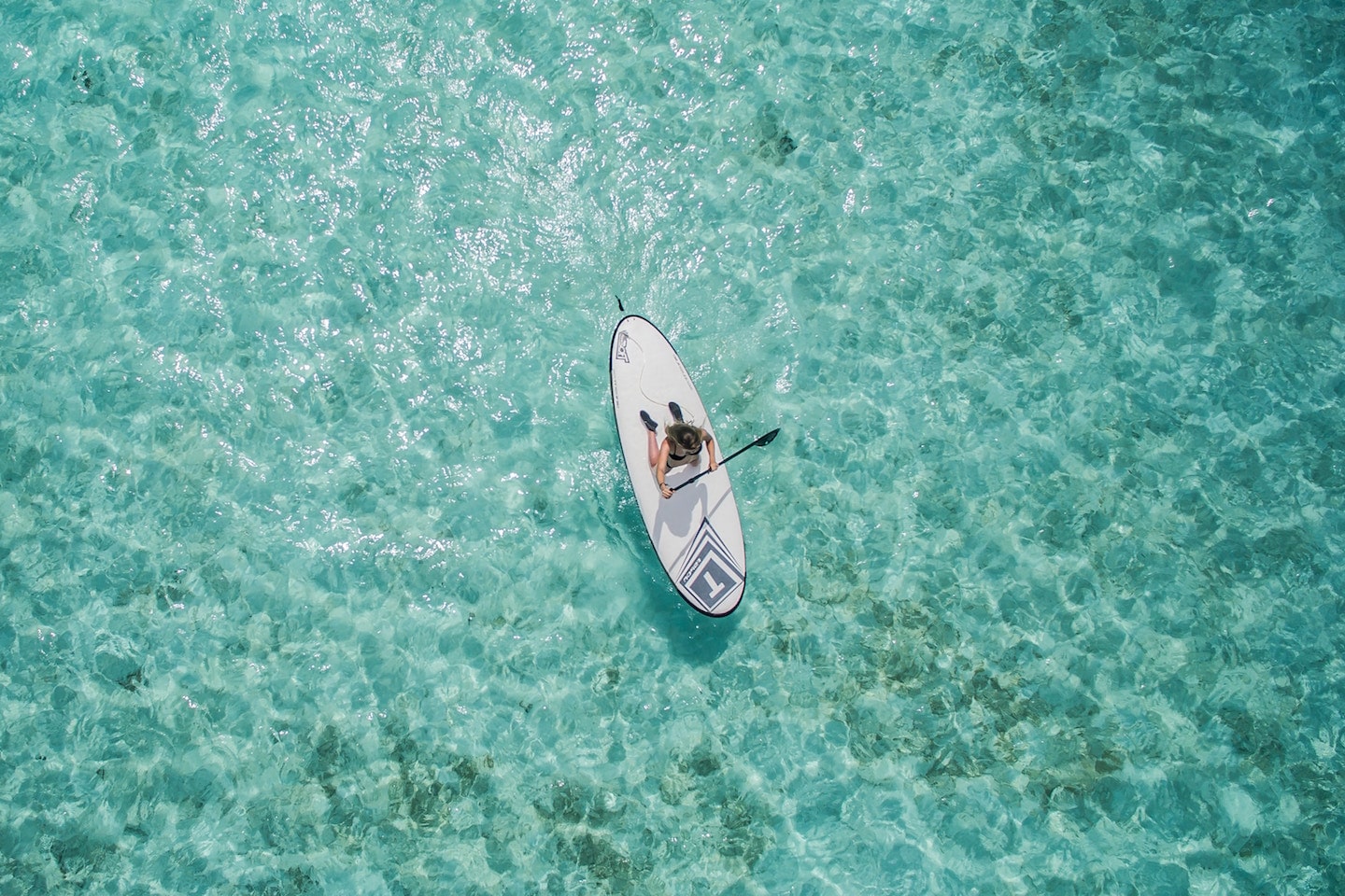 person paddle boarding taken by a drone