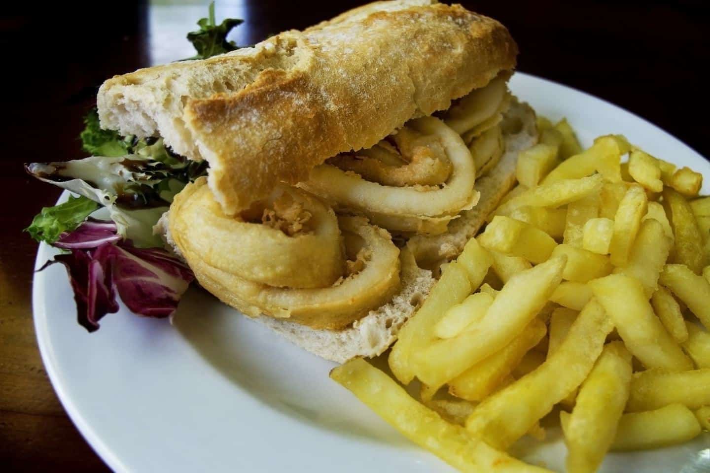 baguette sandwich with fried squid and a side of french fries