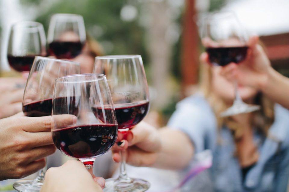 many people cheersing with glasses of red wine