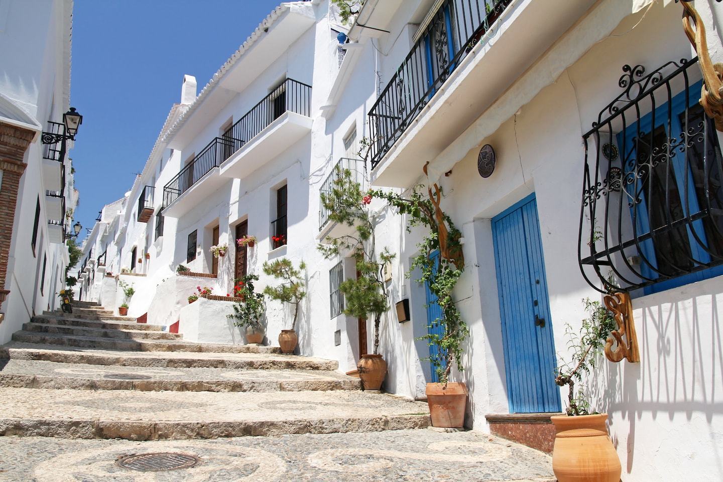 white washed buildings with blue doors and plants in spain