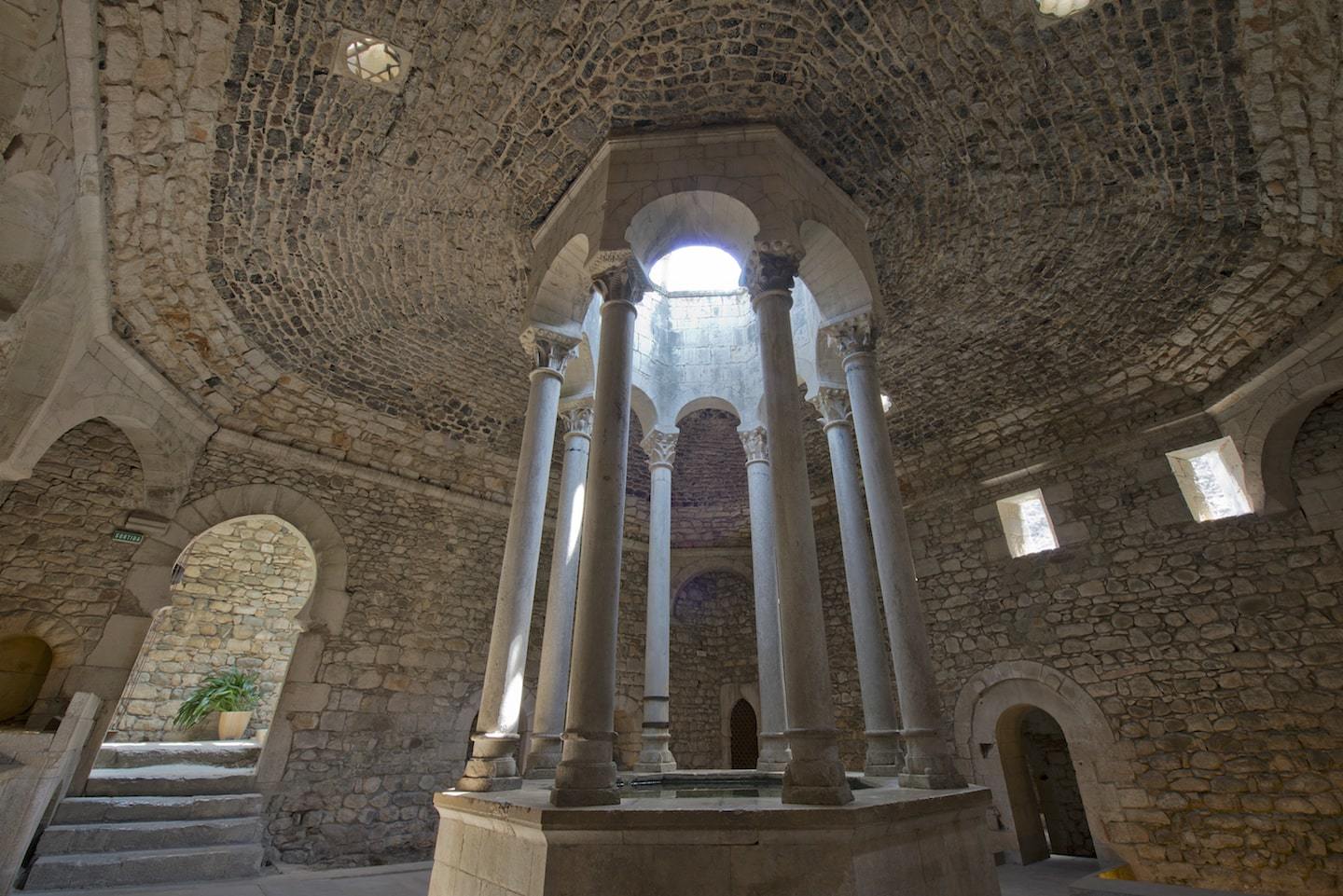 stone bath house with columns and light shining through
