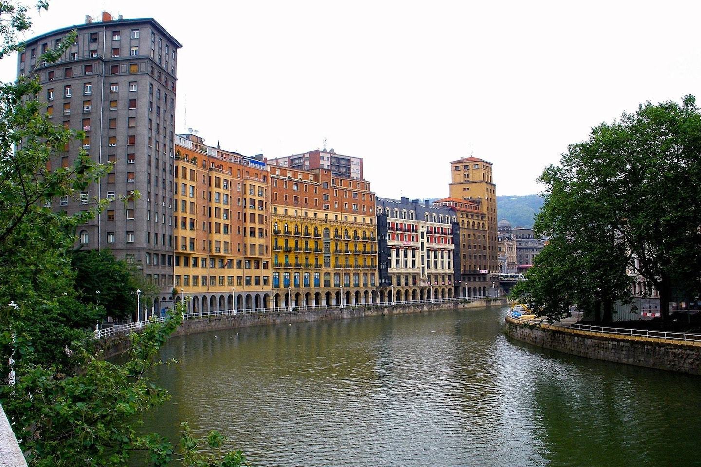 river with buildings on one side and trees on the other