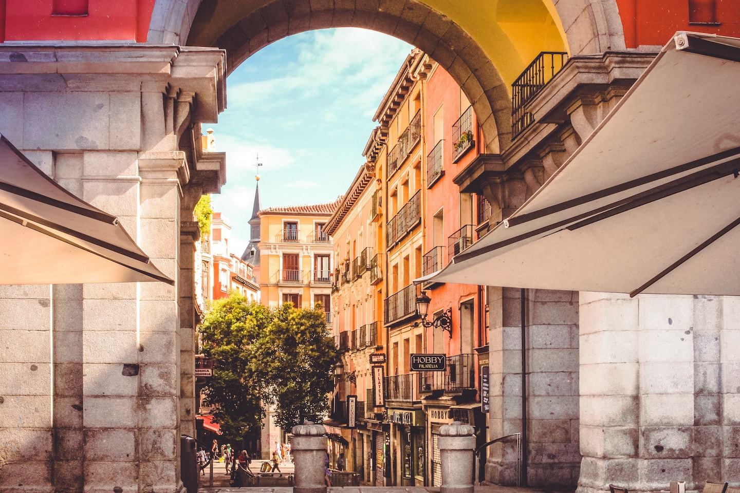 looking through arch at buildings with sun glow in madrid
