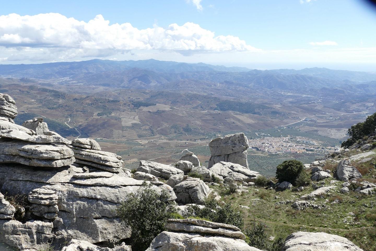 view from top of his with rock formations and mountains and towns in background
