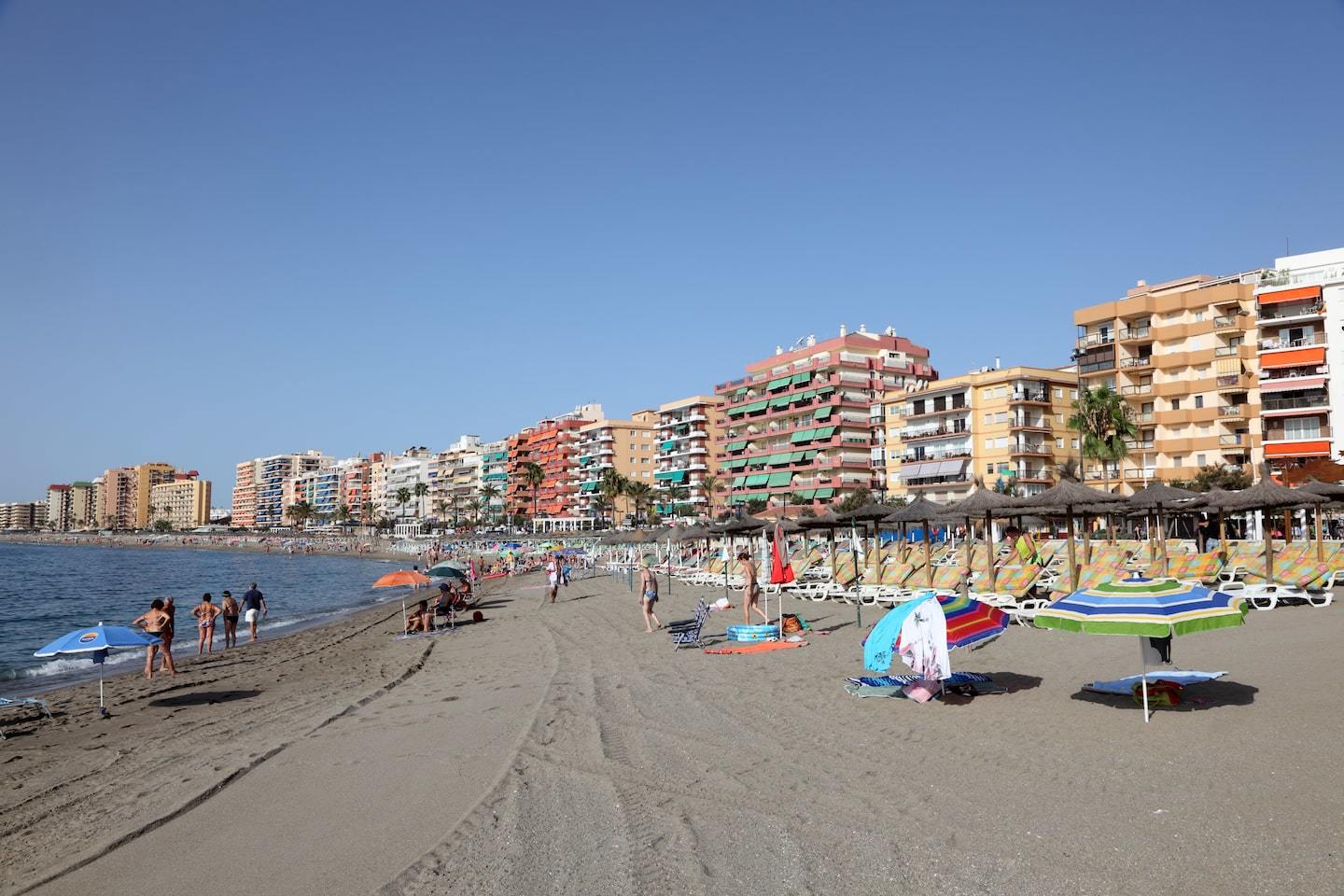 dark sand beach with colorful buildings and blue sky behind