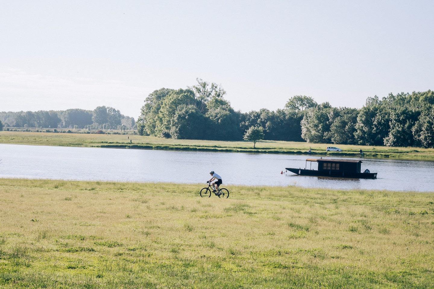 person riding a bike next to the loire river in France