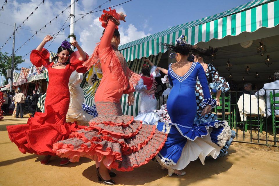 women twirling in flamenco dresses for Feria de Sevilla in Spain