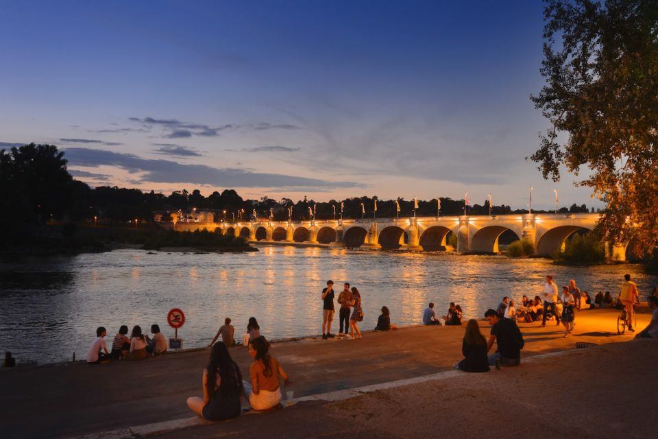 View of the Loire River in France at night with a bridge lit up.