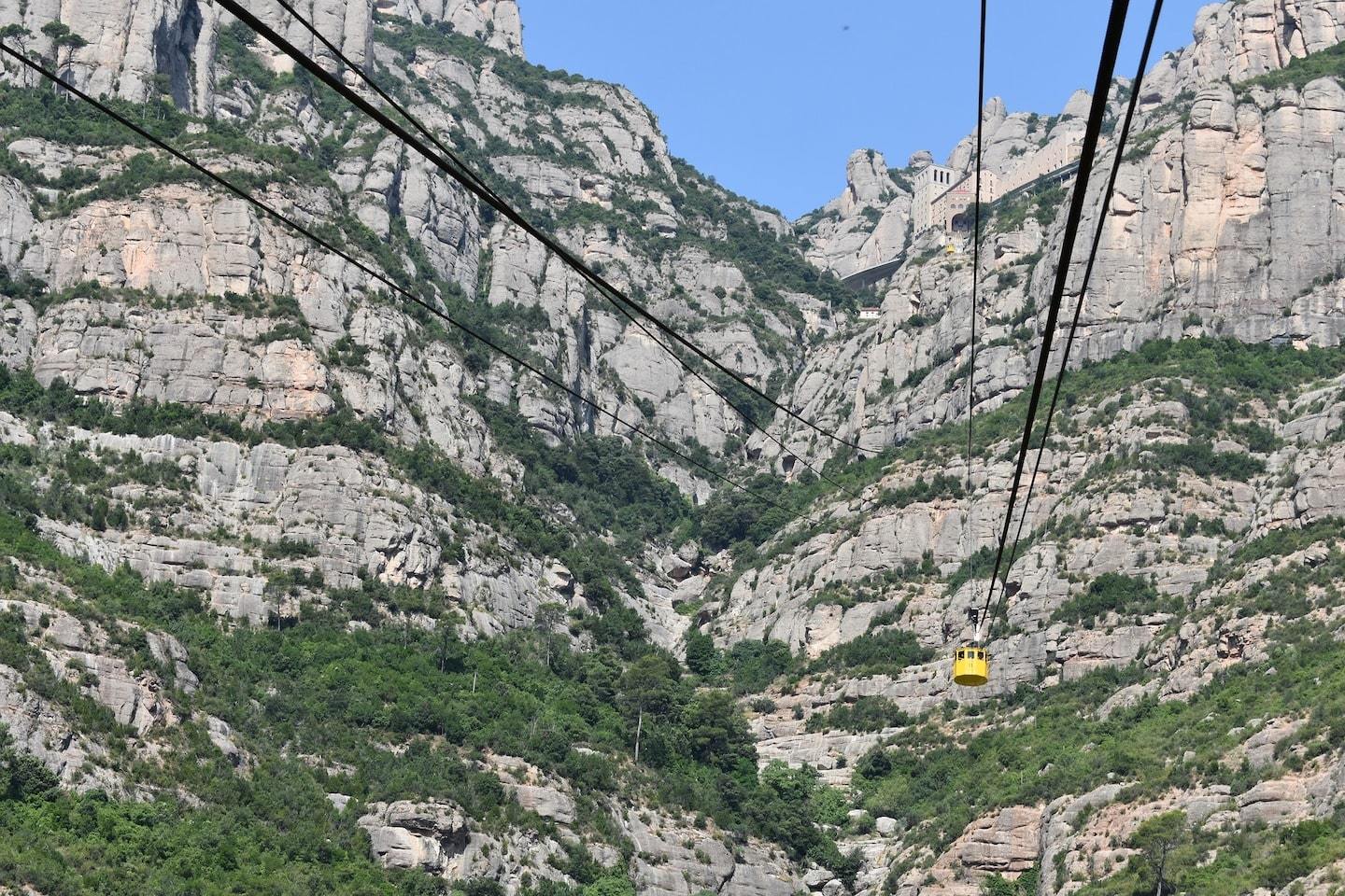 rocky green mountains with yellow cable car