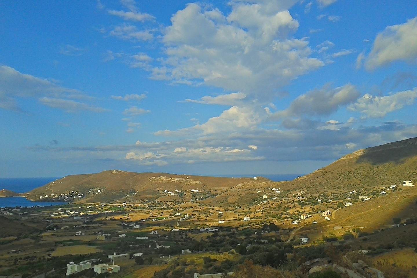 huge expanse of hills dotted with houses with blue sky behind in Andros greece