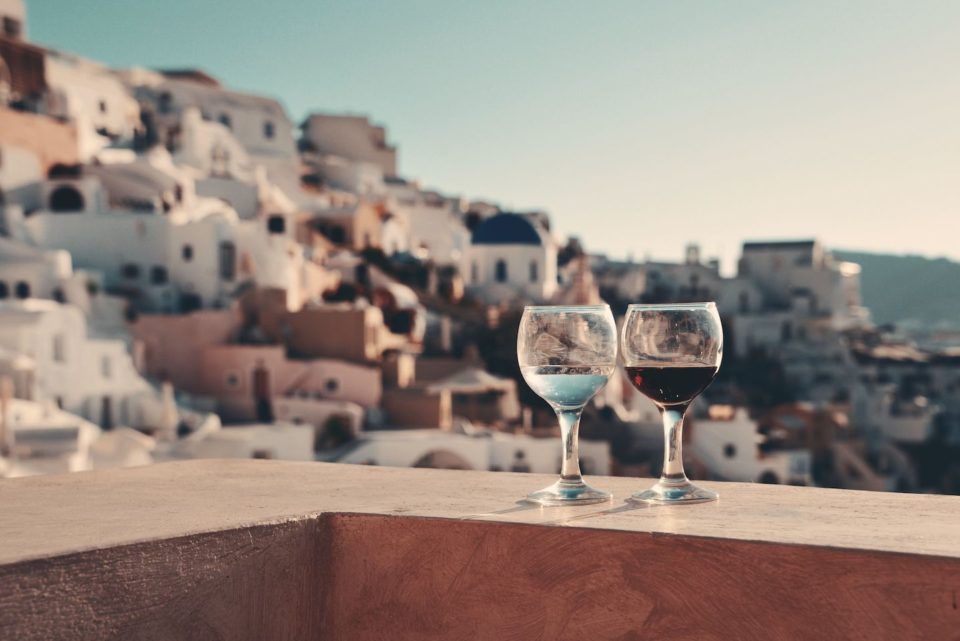 Two classes of wine on a ledge looking out at Santorini Greece
