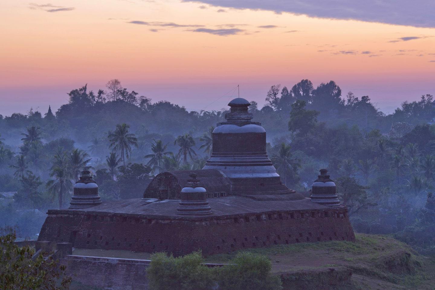 Ancient temple in Myanmar at sunset with black stupas