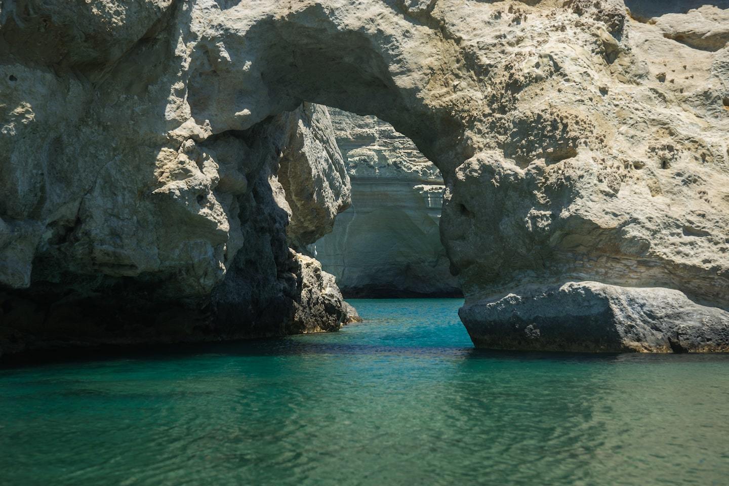 Rock formations making an arch over clear water at Kleftiko Beach in Greece