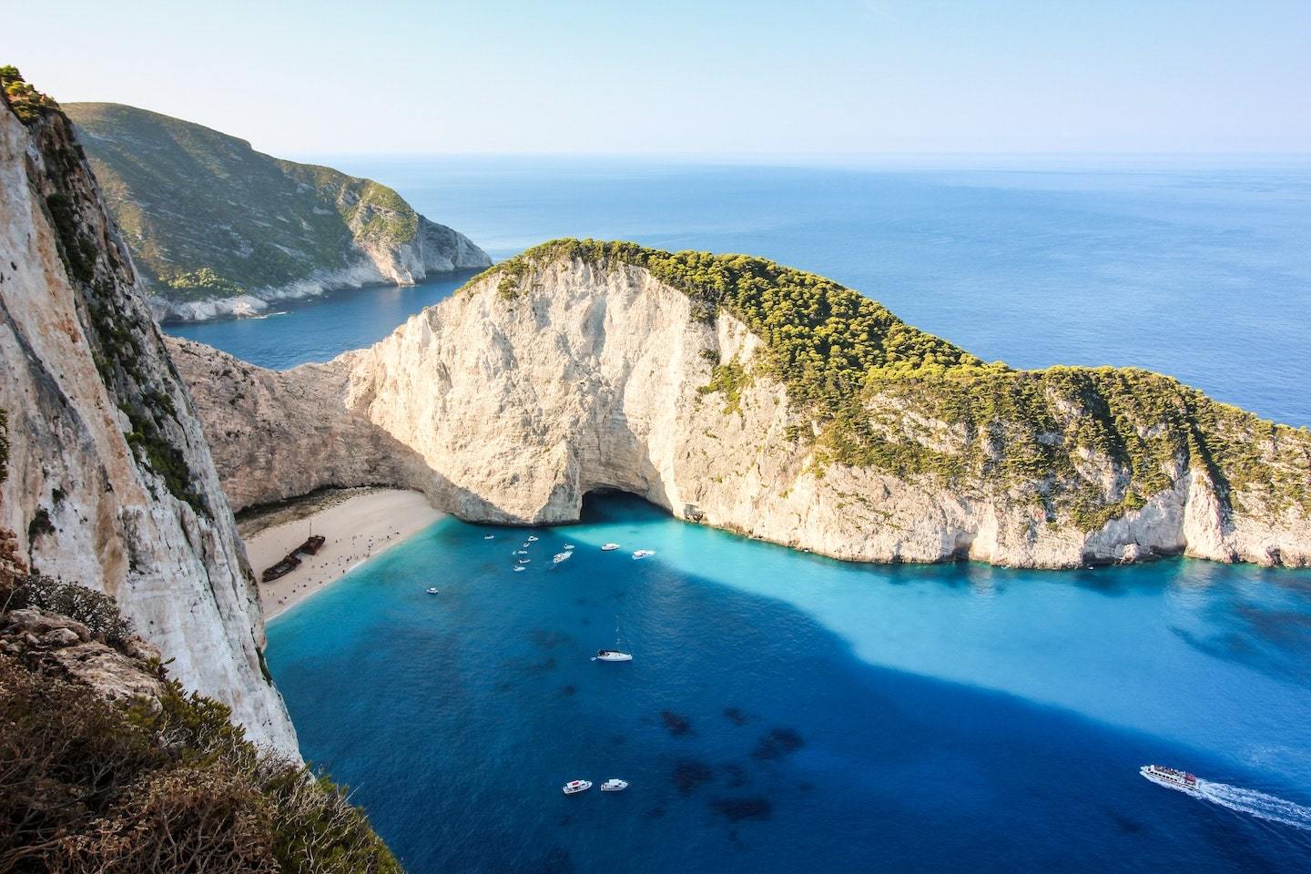 View of Shipwreck Cove in Zakynthos, Greece - a small beach surrounded by curved, rocky cliffs.