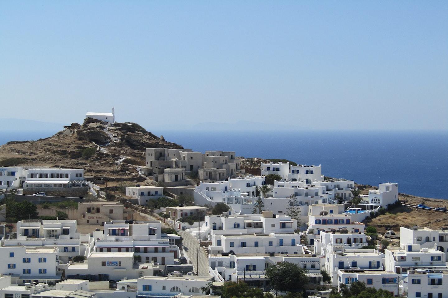 white houses on mountainside with sea behind in ios Greece