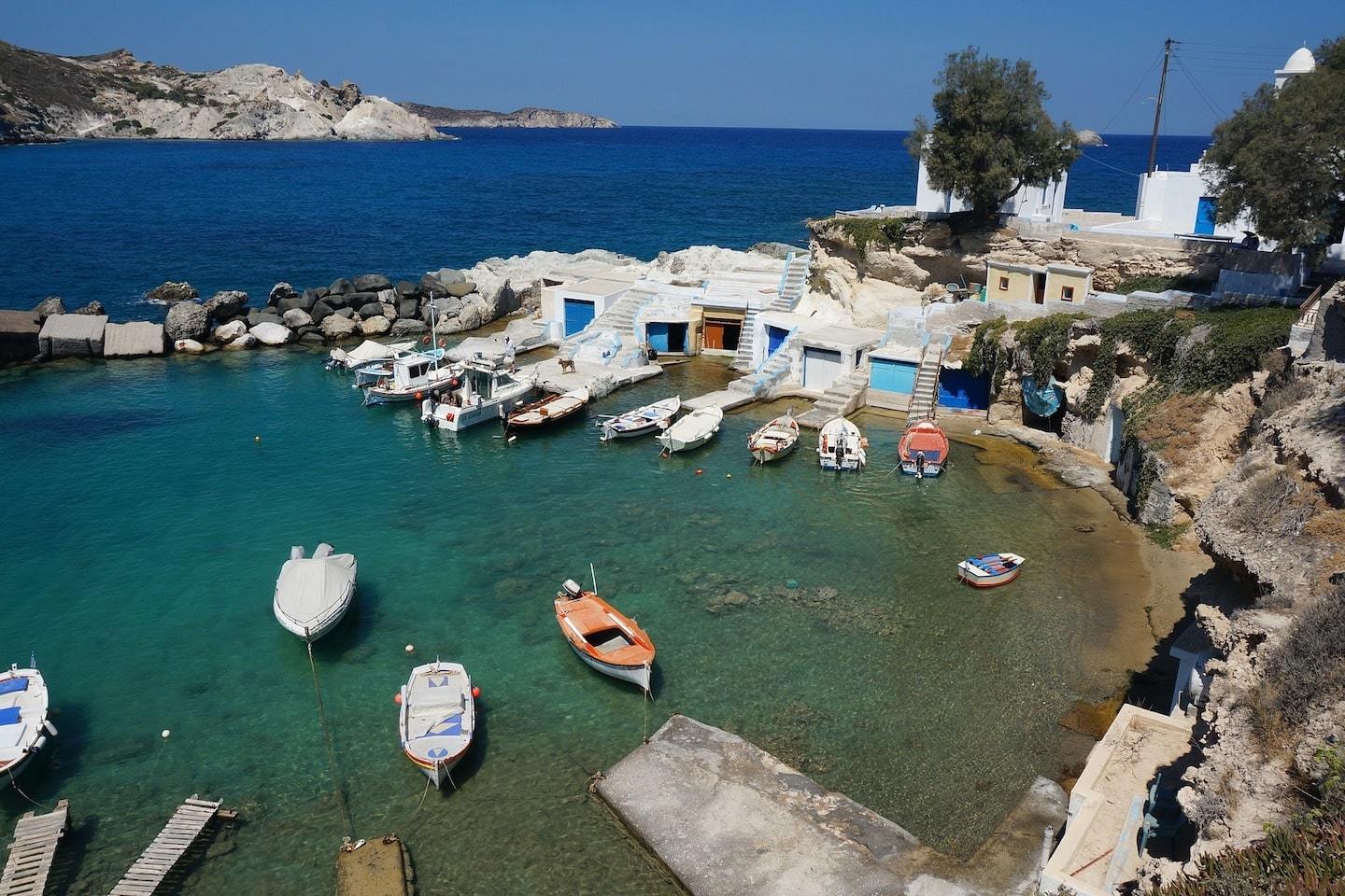 aerial view of bay in Milos Greece with boats, houses and a small beach
