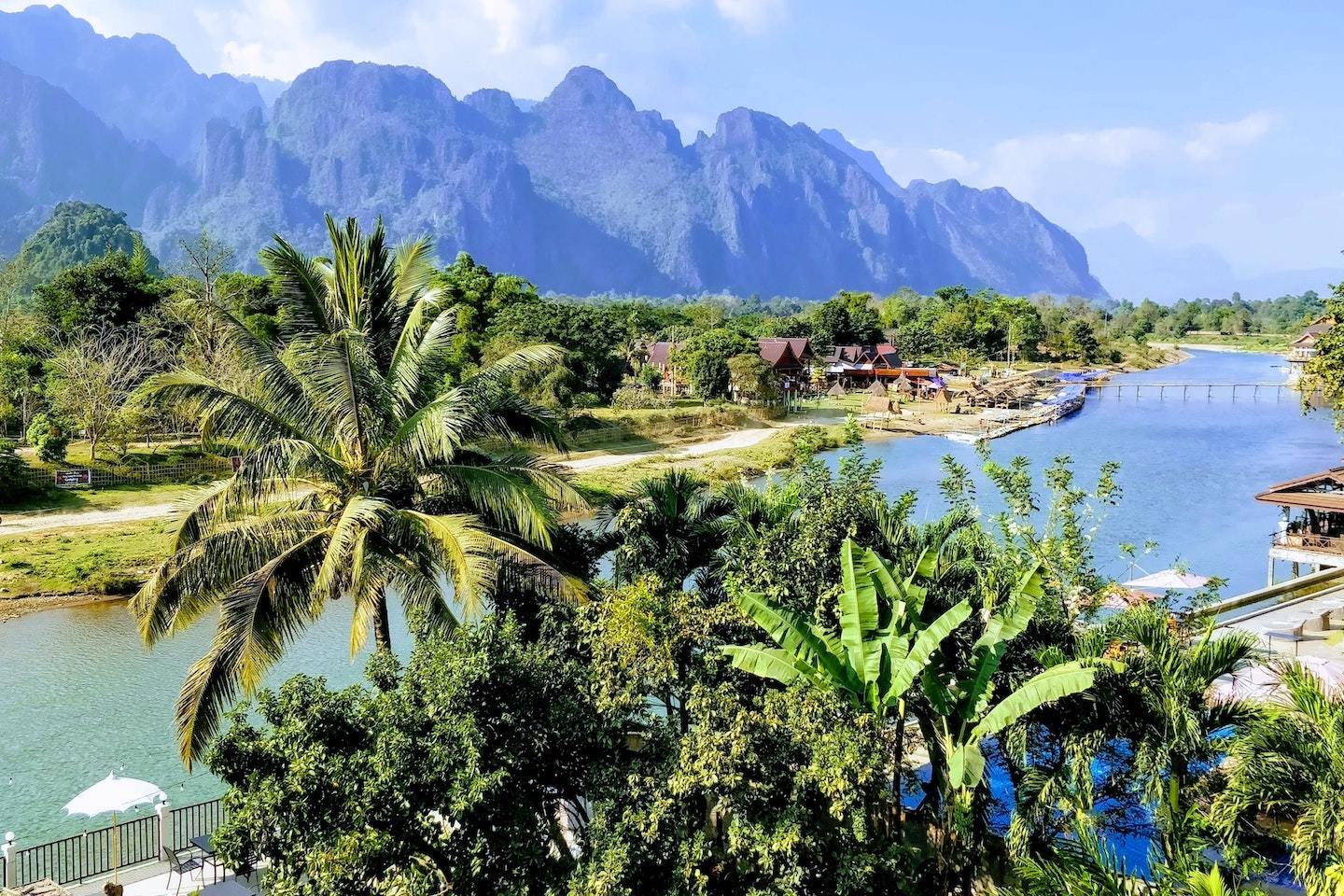 river surrounded by trees and Rocky Mountains in Vang Vieng Laos
