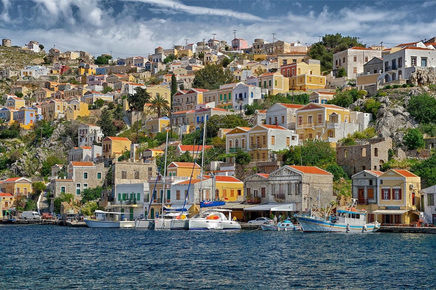 Greek island: colorful buildings on a hilltop with boats and sea in front in Symi Greece