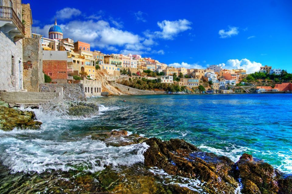 colorful houses sitting above sea in syros greece