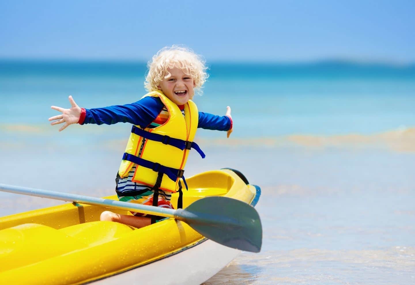 Happy kid on a yellow kayak