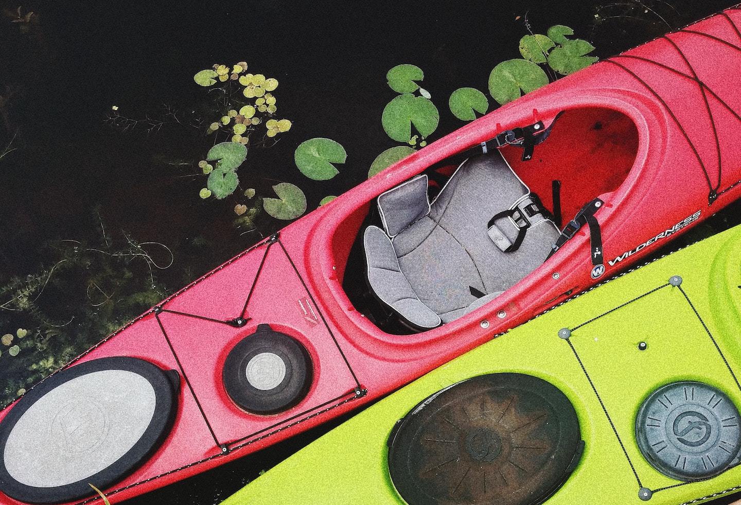 two kayaks with a seat floating on lily pads